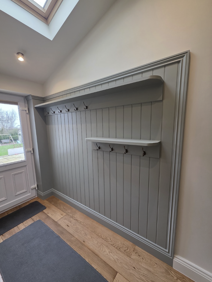 Bespoke grey-green cloakroom panelling with integrated hooks and shelving