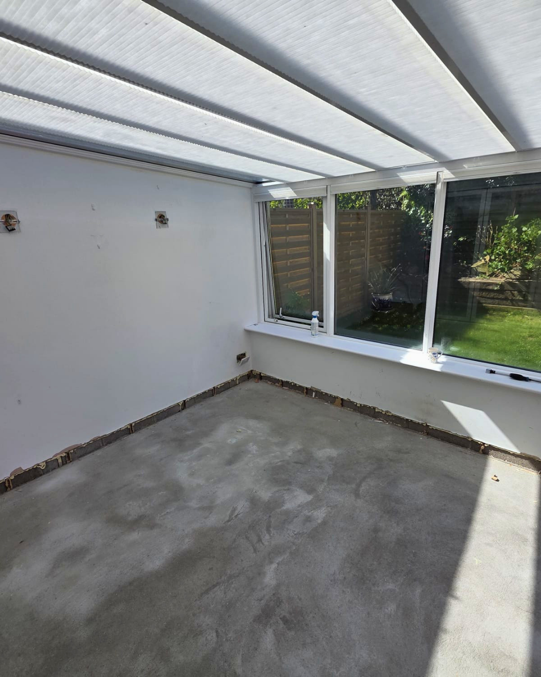Conservatory before works with stripped floor edges and bare walls