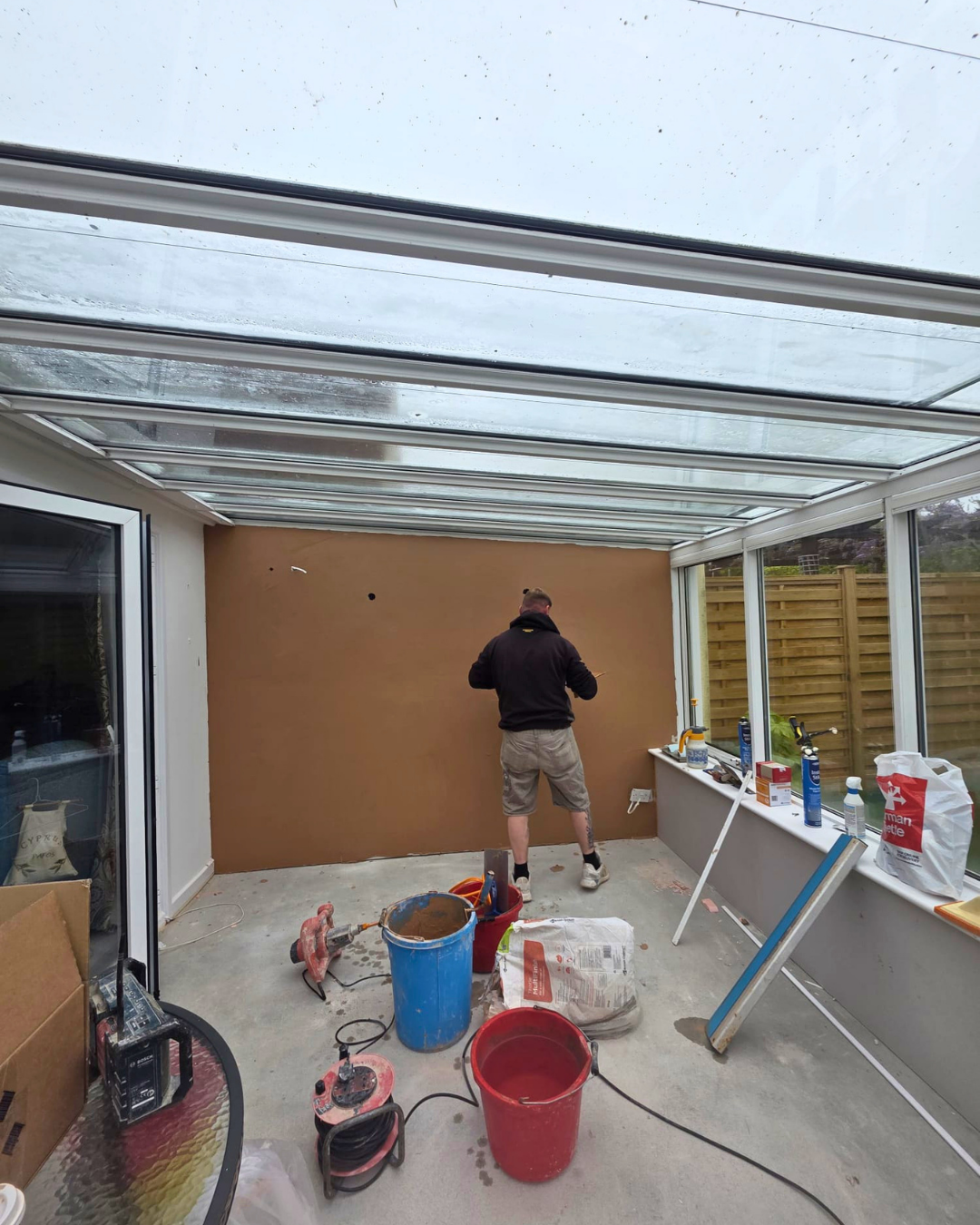 Fresh plaster being applied to conservatory wall during remedial works