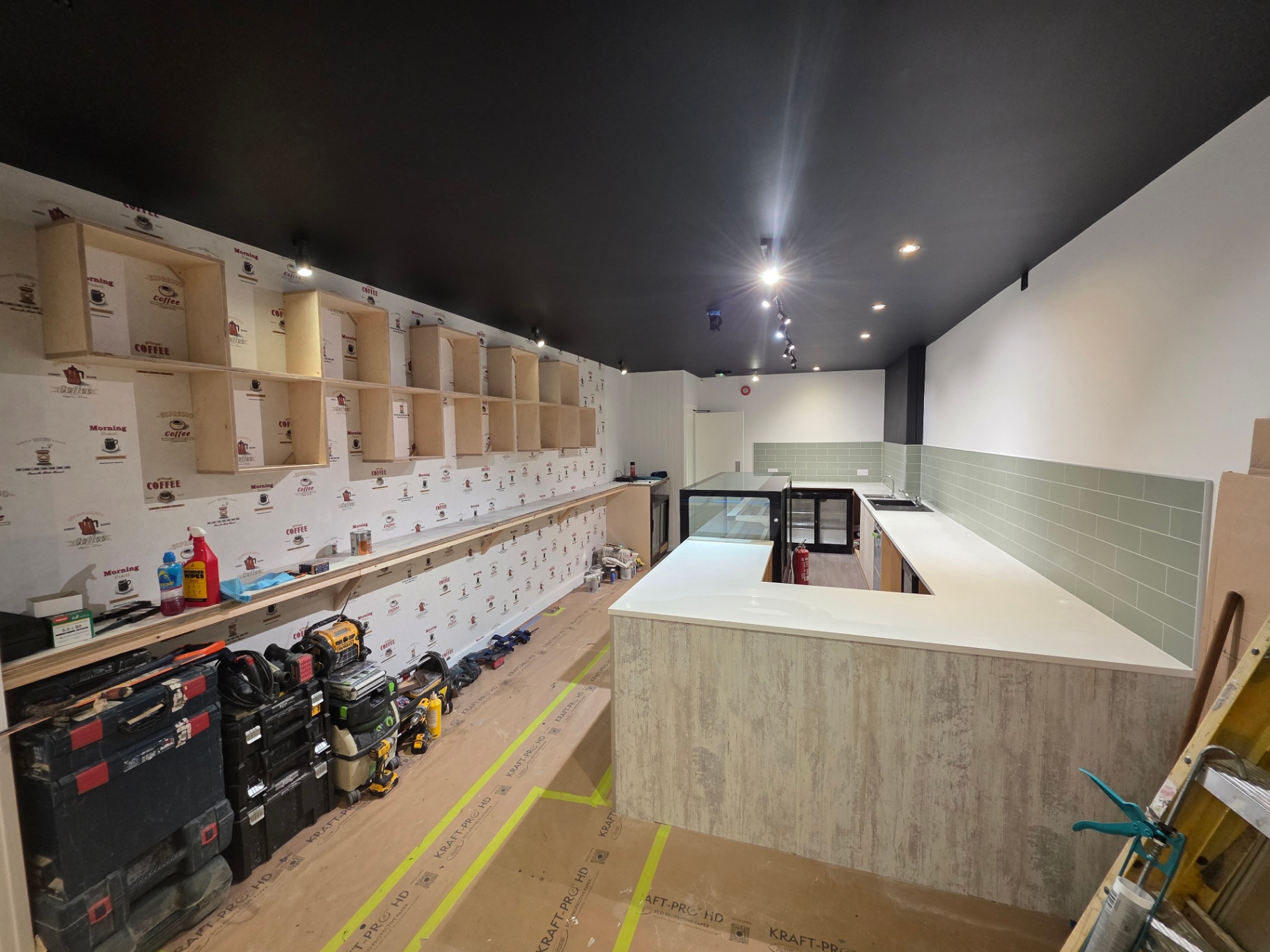 Café fit-out in progress with custom birch-ply shelving installed and counter in place