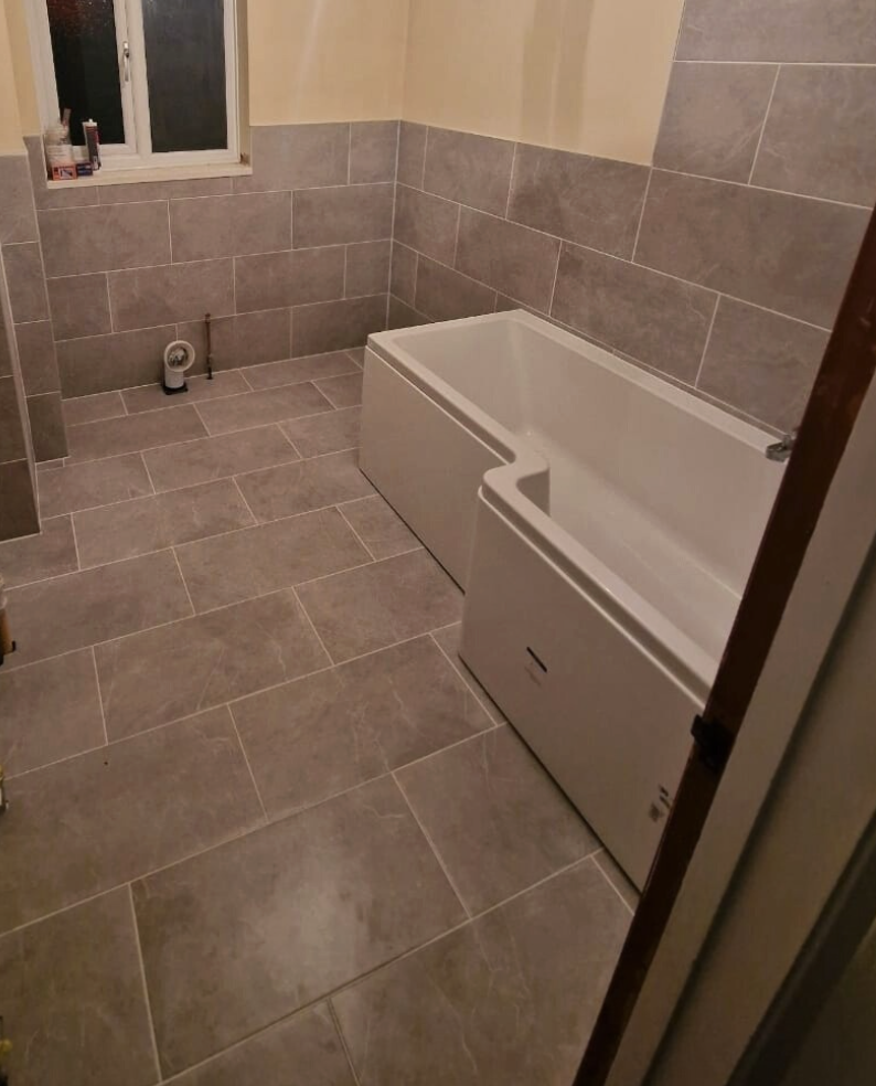 Finished bathroom retiled with large-format grey tiles in Guernsey